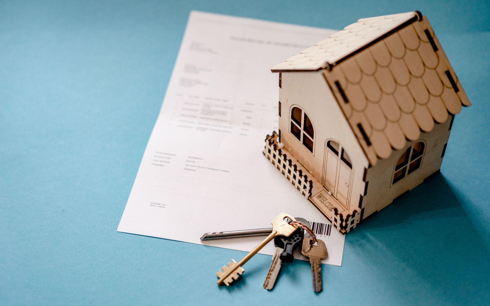 House keys and a lease contract beside a model home
